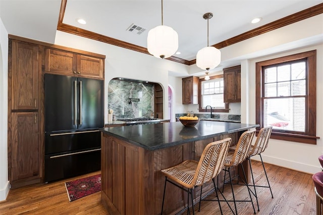 814 NE 18th St, Oklahoma City, OK 73105 - kitchen featuring freestanding refrigerator, dark countertops, crown molding, a breakfast bar, and decorative light fixtures