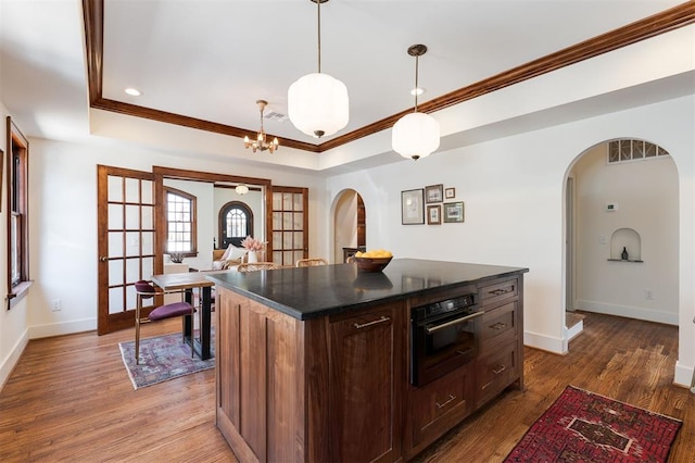 814 NE 18th St, Oklahoma City, OK 73105 - kitchen featuring black oven, a tray ceiling, arched walkways, ornamental molding, and dark countertops