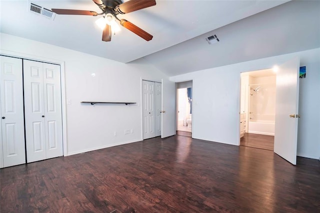 201 E 2nd St, Stroud, OK 74079 - unfurnished bedroom with two closets, lofted ceiling, wood finished floors, connected bathroom, and ceiling fan