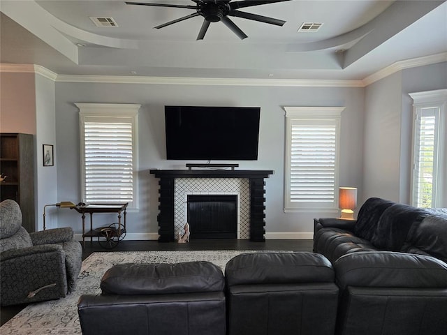 9252 Elaine Dr, Midwest City, OK 73130 - living area featuring a ceiling fan, a tray ceiling, wood finished floors, a fireplace, and crown molding