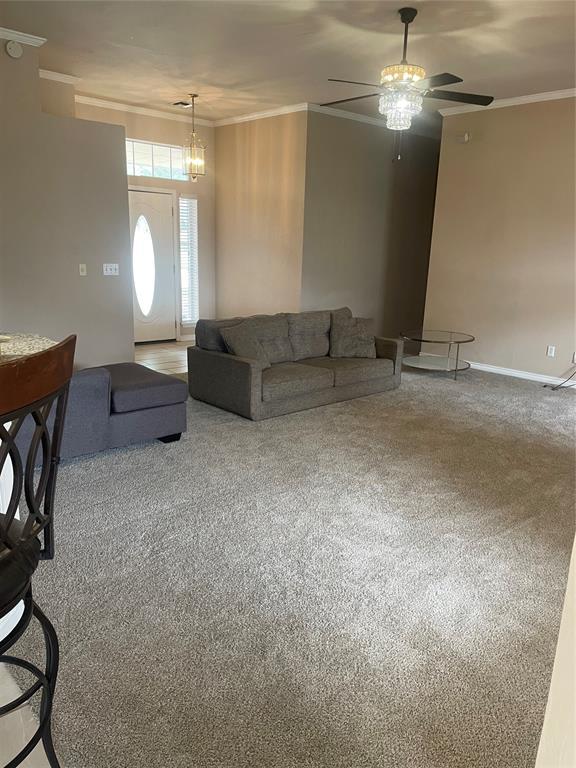 5725 SE 86th St, Oklahoma City, OK 73135 - carpeted living area with ceiling fan, crown molding, and a chandelier