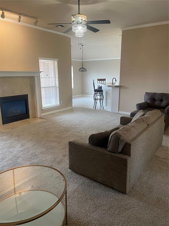 5725 SE 86th St, Oklahoma City, OK 73135 - living area with ornamental molding, track lighting, ceiling fan, carpet floors, and a fireplace