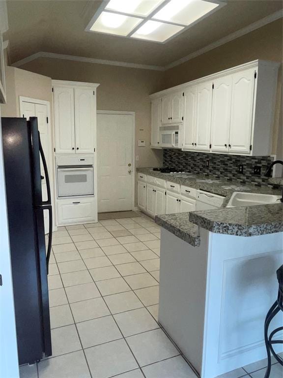 5725 SE 86th St, Oklahoma City, OK 73135 - kitchen featuring white appliances, a peninsula, white cabinets, light tile patterned flooring, and crown molding