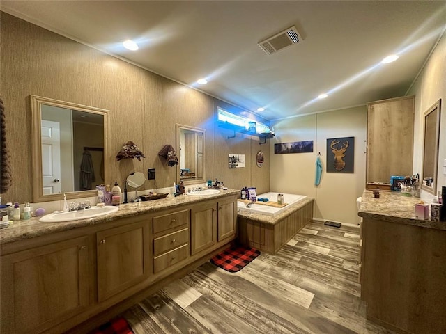 420 N College St, Cordell, OK 73632 - bathroom featuring wood finished floors, double vanity, a garden tub, vaulted ceiling, and recessed lighting