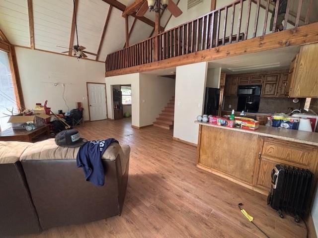 11825 N 3660th Rd, Cromwell, OK 74884 - living room featuring a ceiling fan, light wood-style flooring, stairs, radiator heating unit, and high vaulted ceiling