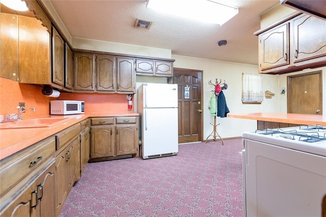 1319 N Cook, Cordell, OK 73632 - kitchen featuring white appliances, light colored carpet, light countertops, and brown cabinetry