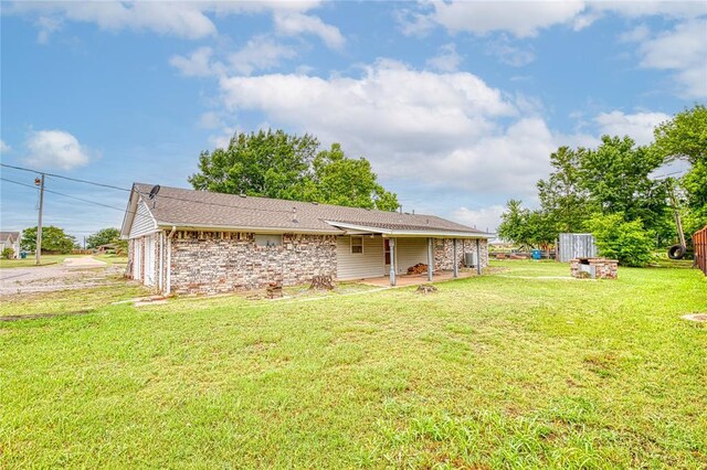 1319 N Cook, Cordell, OK 73632 - rear view of house featuring a patio, a yard, a shingled roof, and brick siding