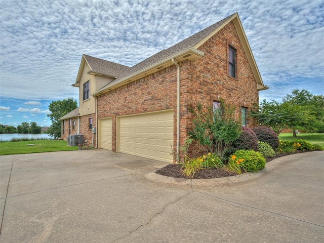 3004 Twin Lake Dr, Moore, OK 73165 - view of property exterior featuring concrete driveway, brick siding, a water view, and a lawn