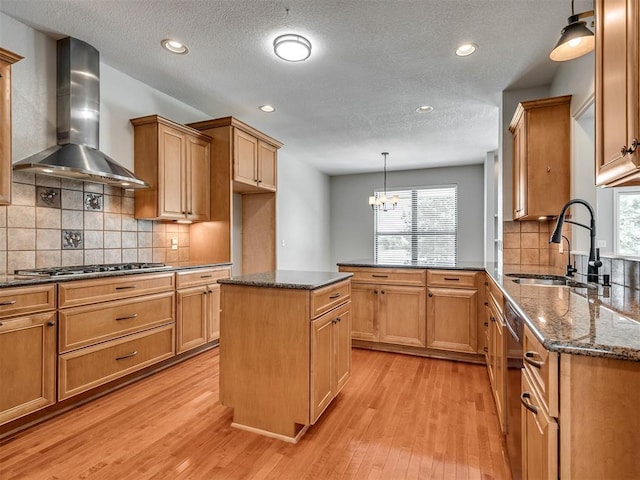 3004 Twin Lake Dr, Moore, OK 73165 - kitchen with wall chimney exhaust hood, appliances with stainless steel finishes, light wood finished floors, dark stone countertops, and a peninsula