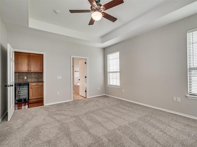 3004 Twin Lake Dr, Moore, OK 73165 - unfurnished bedroom featuring beverage cooler, carpet floors, a tray ceiling, ensuite bath, and a ceiling fan