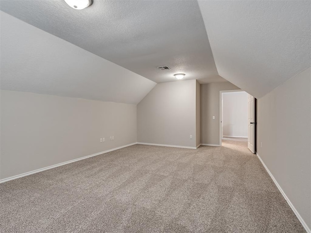 3004 Twin Lake Dr, Moore, OK 73165 - additional living space with a textured ceiling, lofted ceiling, and light colored carpet