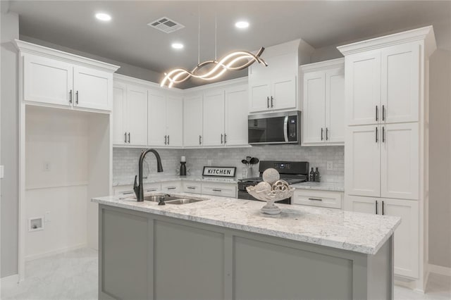 219 SE 45th St, Oklahoma City, OK 73129 - kitchen featuring stainless steel microwave, range, white cabinetry, a center island with sink, and recessed lighting