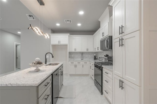 219 SE 45th St, Oklahoma City, OK 73129 - kitchen with appliances with stainless steel finishes, white cabinetry, a center island with sink, light stone countertops, and recessed lighting
