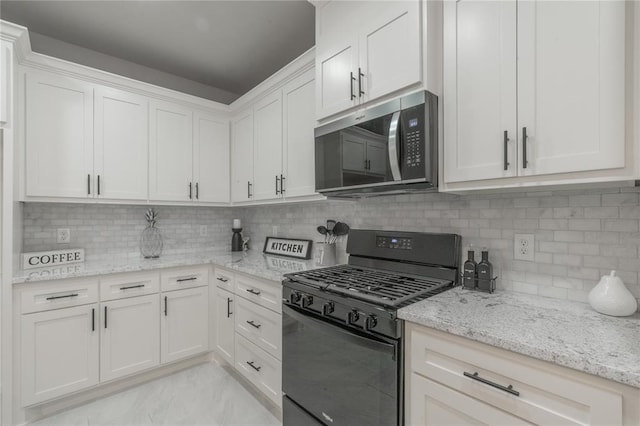 219 SE 45th St, Oklahoma City, OK 73129 - kitchen featuring stainless steel microwave, gas stove, white cabinetry, light stone counters, and tasteful backsplash