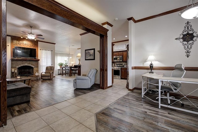 10633 NW 38th St, Yukon, OK 73099 - living area with crown molding, light tile patterned floors, a fireplace with raised hearth, a ceiling fan, and a desk