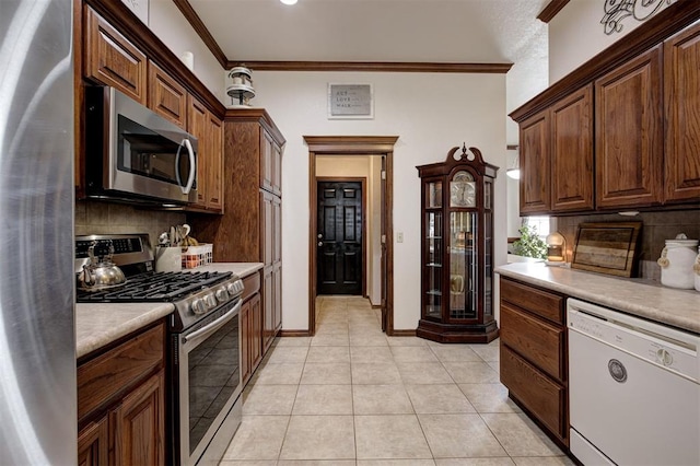 10633 NW 38th St, Yukon, OK 73099 - kitchen featuring stainless steel appliances, backsplash, light countertops, crown molding, and light tile patterned floors
