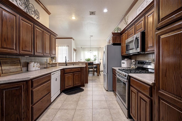 10633 NW 38th St, Yukon, OK 73099 - kitchen featuring appliances with stainless steel finishes, tasteful backsplash, a peninsula, crown molding, and light countertops