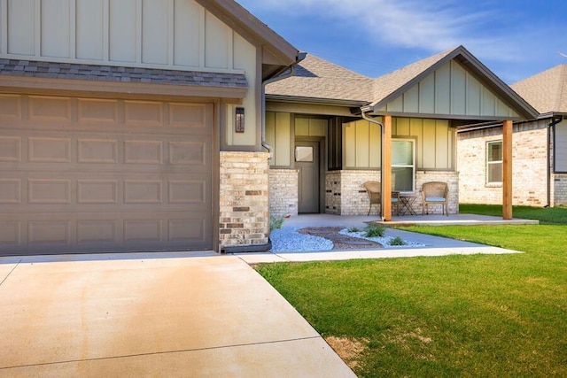 9228 NW 144th Pl, Yukon, OK 73099 - view of front of home featuring board and batten siding, a front lawn, roof with shingles, concrete driveway, and stone siding