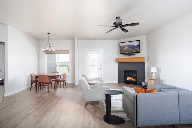 9228 NW 144th Pl, Yukon, OK 73099 - living room featuring a glass covered fireplace, light wood-style floors, a ceiling fan, and a chandelier