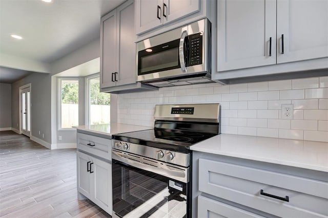 1317 E Boyd St, Norman, OK 73071 - kitchen featuring appliances with stainless steel finishes, gray cabinets, light countertops, light wood-style floors, and tasteful backsplash