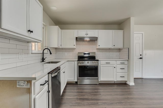 3325 NW 65th St Unit 4057723241, Oklahoma City, OK 73116 - kitchen featuring appliances with stainless steel finishes, under cabinet range hood, light countertops, white cabinetry, and dark wood-type flooring