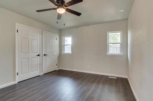 3325 NW 65th St Unit 4057723241, Oklahoma City, OK 73116 - unfurnished bedroom featuring multiple windows, dark wood-style flooring, and a ceiling fan