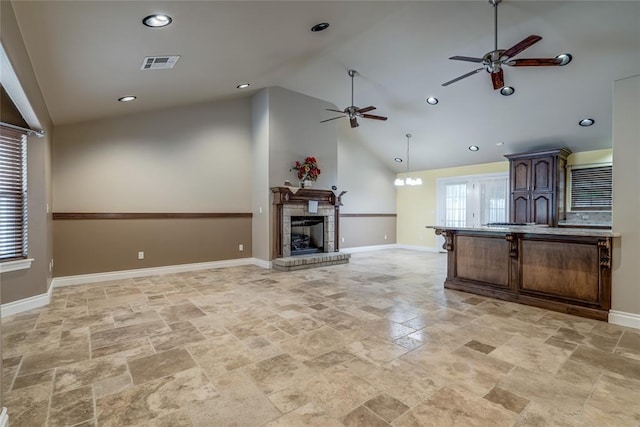 6704 Tall Oaks Dr, Oklahoma City, OK 73127 - kitchen featuring a ceiling fan, light stone finish floors, a kitchen breakfast bar, open floor plan, and a fireplace with raised hearth