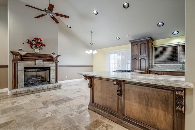 6704 Tall Oaks Dr, Oklahoma City, OK 73127 - kitchen with light stone countertops, a ceiling fan, hanging light fixtures, a breakfast bar area, and high vaulted ceiling
