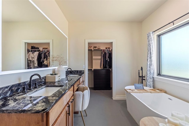 1074 Fawn Meadow Dr, Blanchard, OK 73010 - full bathroom featuring double vanity, a freestanding tub, a walk in closet, and concrete floors