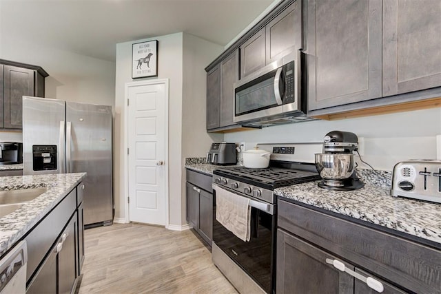 10409 NW 25th St, Yukon, OK 73099 - kitchen with appliances with stainless steel finishes, light wood-style floors, dark brown cabinets, and light stone counters