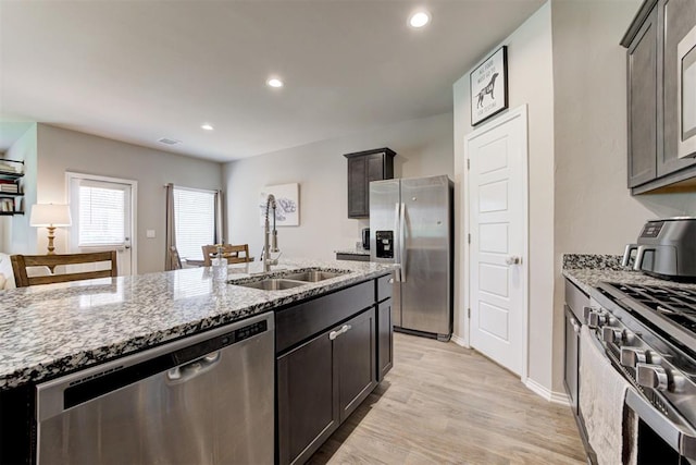 10409 NW 25th St, Yukon, OK 73099 - kitchen with appliances with stainless steel finishes, light stone counters, light wood-style floors, recessed lighting, and dark brown cabinets