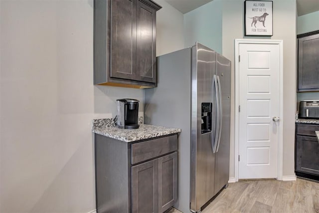 10409 NW 25th St, Yukon, OK 73099 - kitchen featuring stainless steel refrigerator with ice dispenser, dark brown cabinets, light wood-style floors, and light stone counters