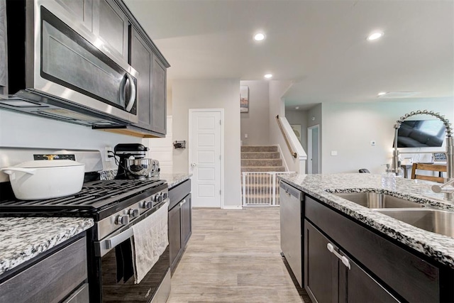 10409 NW 25th St, Yukon, OK 73099 - kitchen with appliances with stainless steel finishes, light stone counters, light wood-style floors, recessed lighting, and dark brown cabinetry