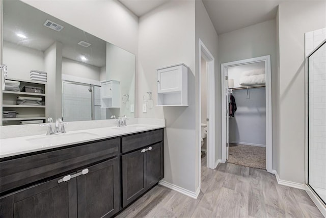 10409 NW 25th St, Yukon, OK 73099 - full bathroom with a stall shower, a walk in closet, wood finished floors, and double vanity