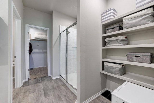 10409 NW 25th St, Yukon, OK 73099 - bathroom featuring a shower stall, a walk in closet, and wood finished floors