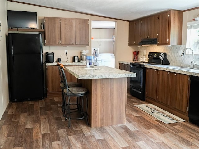 16940 Wildwood Dr, Lexington, OK 73051 - kitchen featuring black appliances, under cabinet range hood, light countertops, dark wood-style flooring, and backsplash