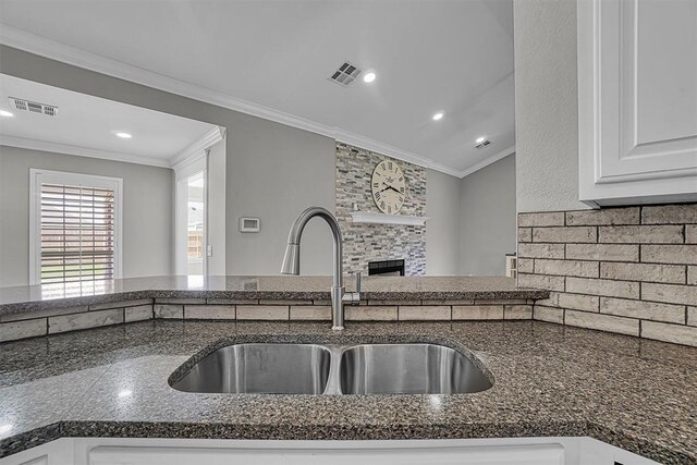 517 N Quail Run, Altus, OK 73521 - kitchen featuring a large fireplace, ornamental molding, white cabinets, dark stone counters, and tasteful backsplash