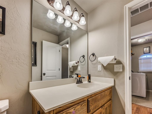 18204 Summer Grove Ave, Edmond, OK 73012 - bathroom with washer / clothes dryer, vanity, wood finished floors, and a textured wall
