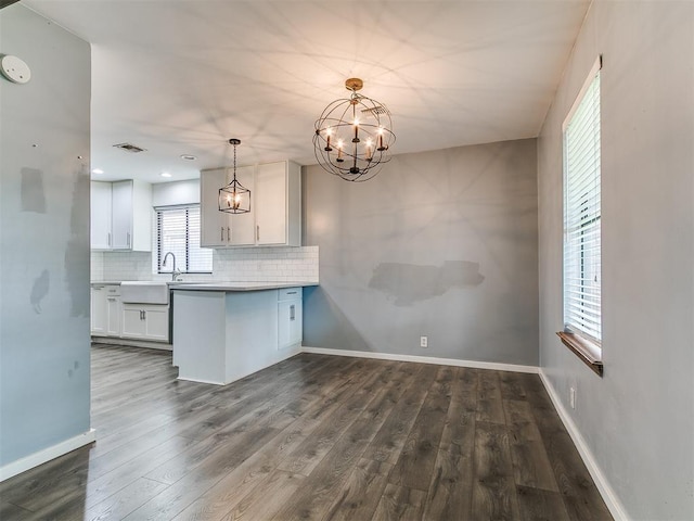 2004 Tanglewood Dr, Edmond, OK 73013 - kitchen featuring white cabinets, decorative backsplash, dark wood-style floors, a chandelier, and a peninsula