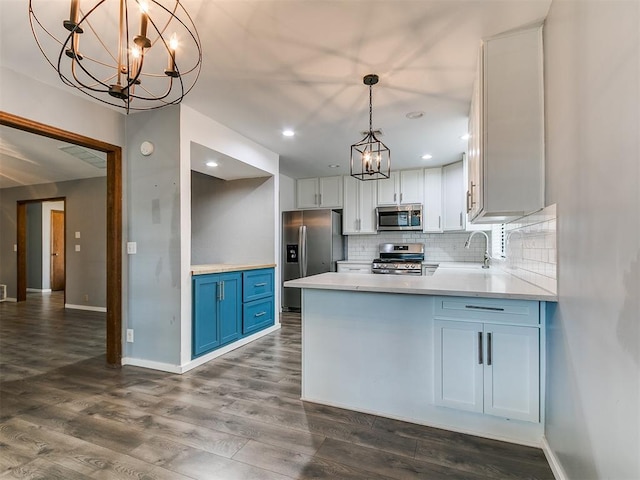 2004 Tanglewood Dr, Edmond, OK 73013 - kitchen featuring appliances with stainless steel finishes, a chandelier, dark wood-type flooring, tasteful backsplash, and light countertops