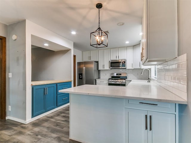2004 Tanglewood Dr, Edmond, OK 73013 - kitchen with stainless steel appliances, dark wood finished floors, tasteful backsplash, blue cabinetry, and a peninsula