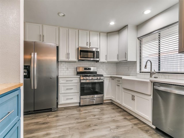 2004 Tanglewood Dr, Edmond, OK 73013 - kitchen with stainless steel appliances, light countertops, backsplash, white cabinetry, and recessed lighting