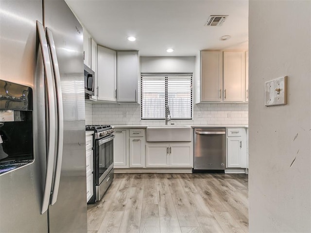 2004 Tanglewood Dr, Edmond, OK 73013 - kitchen with stainless steel appliances, tasteful backsplash, light countertops, light wood-style flooring, and recessed lighting