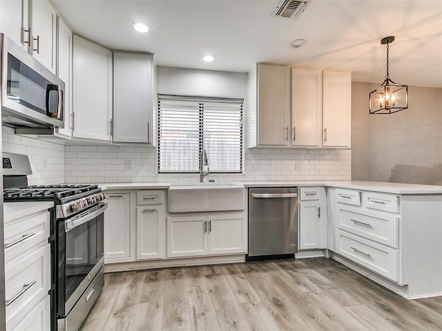 2004 Tanglewood Dr, Edmond, OK 73013 - kitchen with stainless steel appliances, a peninsula, light countertops, a chandelier, and decorative backsplash