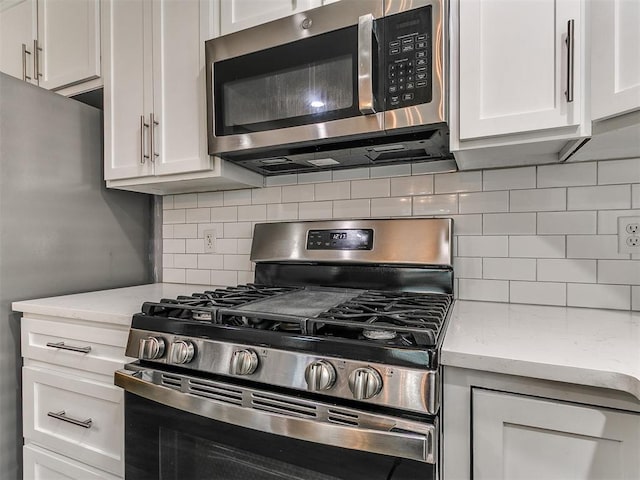 2004 Tanglewood Dr, Edmond, OK 73013 - kitchen with appliances with stainless steel finishes, white cabinets, decorative backsplash, and light stone counters
