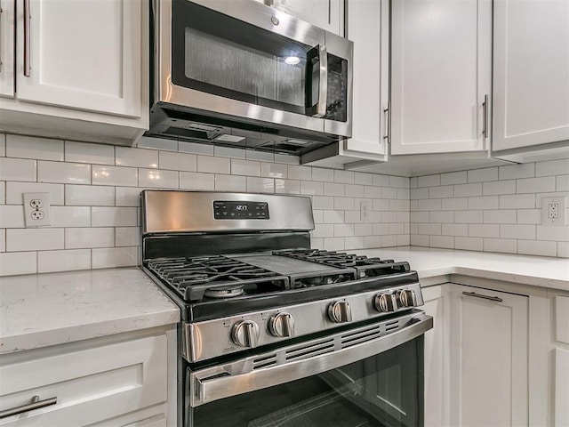 2004 Tanglewood Dr, Edmond, OK 73013 - kitchen featuring appliances with stainless steel finishes, white cabinetry, and tasteful backsplash