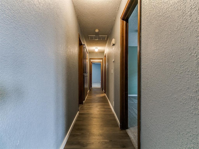 2004 Tanglewood Dr, Edmond, OK 73013 - hallway featuring a textured wall, dark wood finished floors, a textured ceiling, and attic access