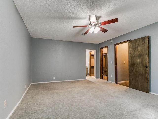 2004 Tanglewood Dr, Edmond, OK 73013 - unfurnished bedroom with carpet, a spacious closet, a textured ceiling, and ceiling fan