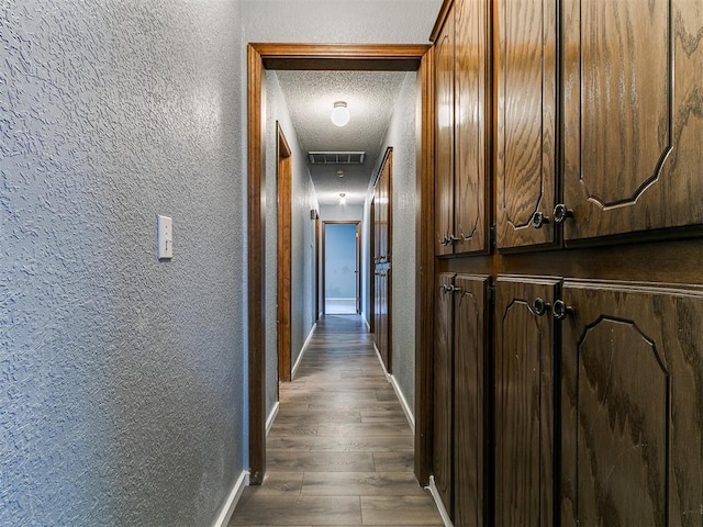 2004 Tanglewood Dr, Edmond, OK 73013 - hall featuring a textured wall, a textured ceiling, and dark wood-type flooring