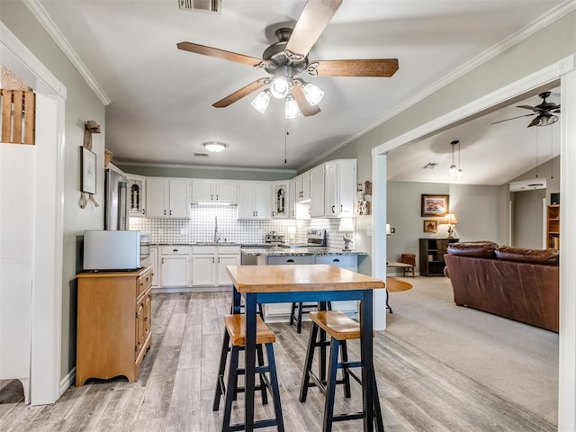 1616 E Cottonwood Rd, Goldsby, OK 73093 - kitchen with ceiling fan, tasteful backsplash, white cabinets, crown molding, and light wood-style floors